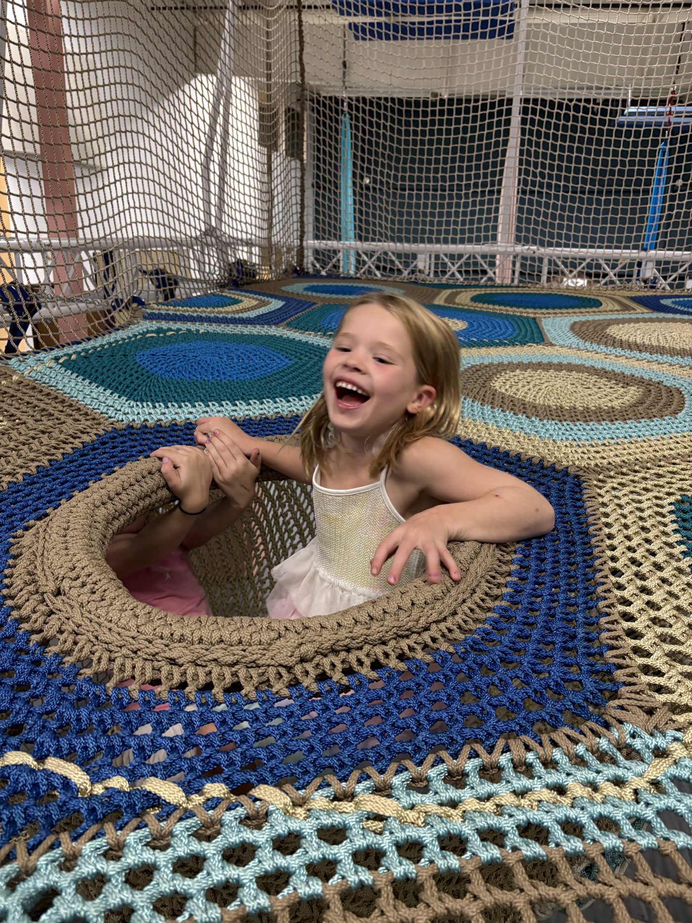 A child laughing in the tree-net climbing structure during open play at Prana Play
